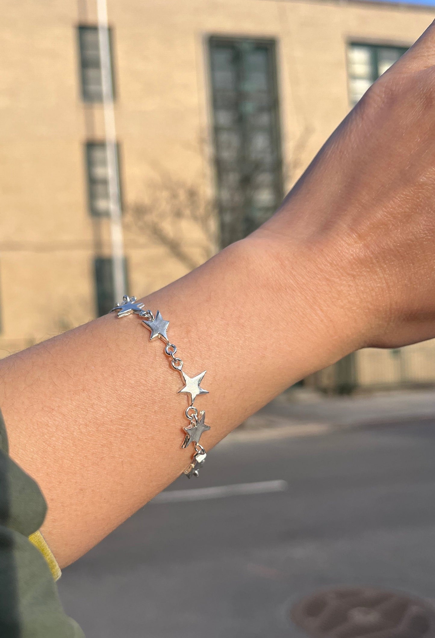 STERLING SILVER STAR LINK BRACELET WORN ON A WRIST UNDER SUNLIGHT